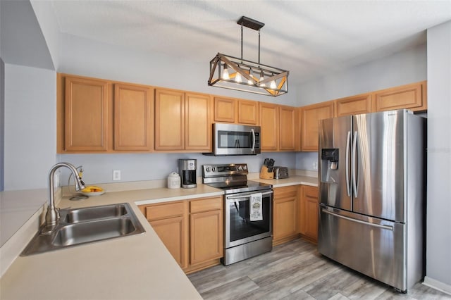 kitchen with stainless steel appliances, sink, hanging light fixtures, and light wood-type flooring