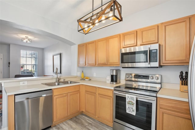 kitchen featuring appliances with stainless steel finishes, light brown cabinetry, sink, hanging light fixtures, and kitchen peninsula