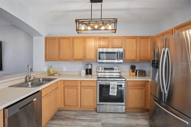 kitchen with light brown cabinetry, sink, pendant lighting, stainless steel appliances, and hardwood / wood-style floors