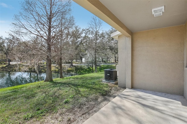 view of yard featuring a water view, a patio, and central air condition unit