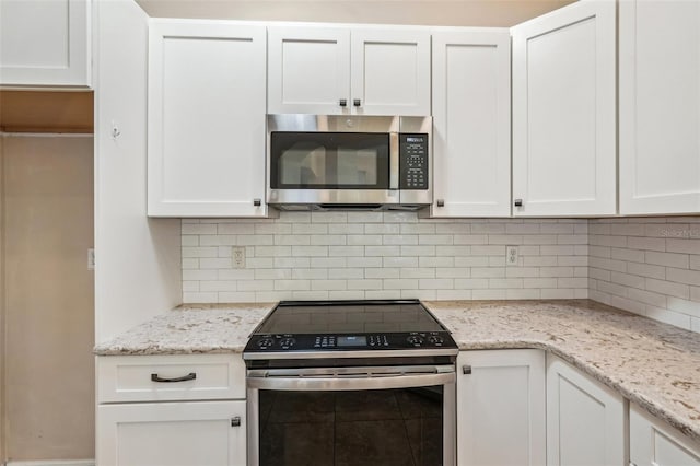 kitchen featuring stainless steel appliances, light stone countertops, and white cabinets