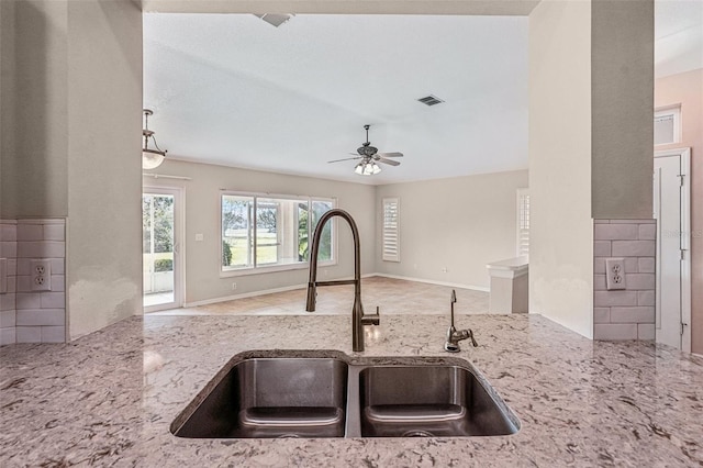 kitchen with light stone countertops, sink, backsplash, and ceiling fan