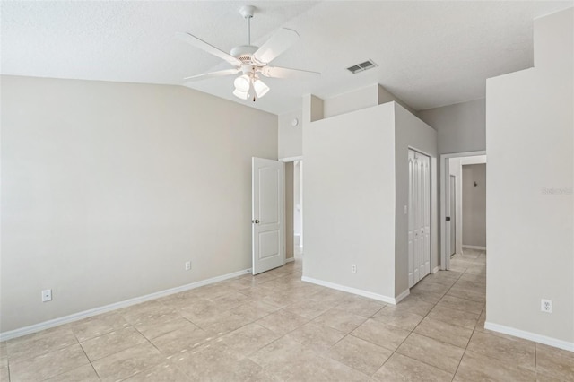 empty room with lofted ceiling, light tile patterned floors, a textured ceiling, and ceiling fan