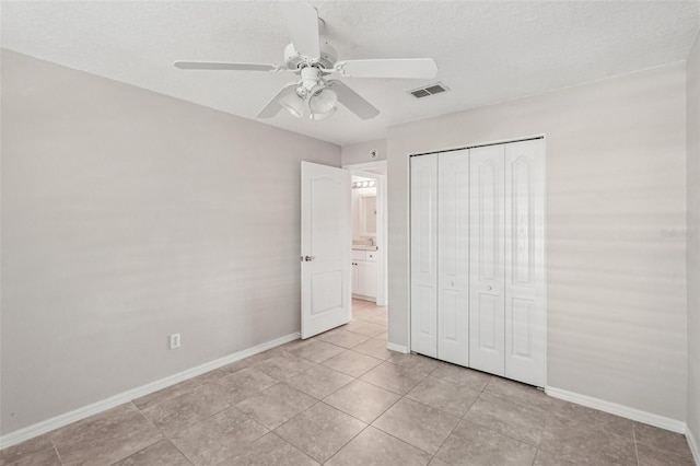 unfurnished bedroom featuring ceiling fan, a closet, a textured ceiling, and light tile patterned flooring