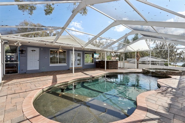 view of swimming pool with an in ground hot tub, glass enclosure, and a patio area