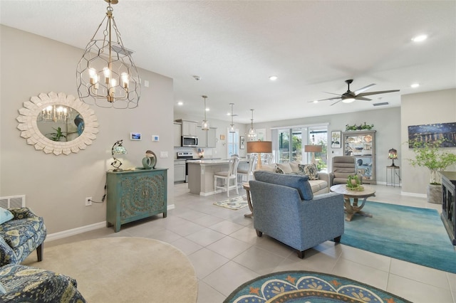 tiled living room featuring ceiling fan with notable chandelier