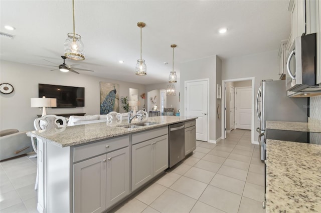 kitchen featuring hanging light fixtures, appliances with stainless steel finishes, sink, and a kitchen island with sink