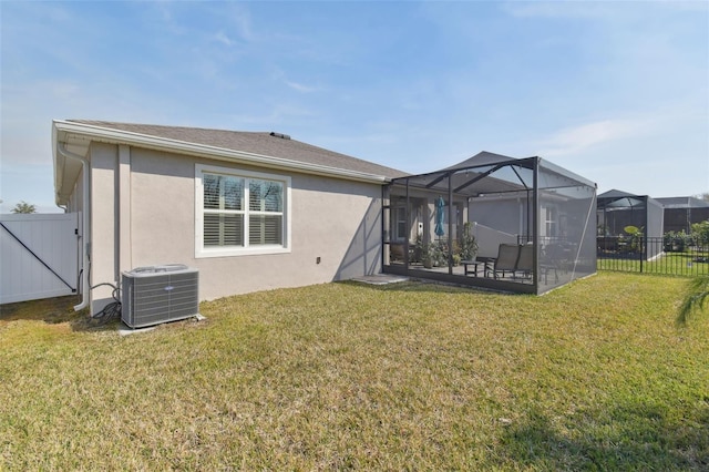 back of property with central AC unit, a lanai, a patio area, and a yard