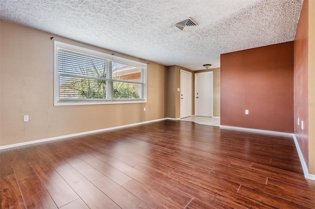 spare room featuring wood-type flooring and a textured ceiling