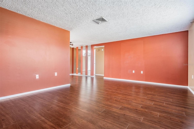 spare room with dark hardwood / wood-style floors and a textured ceiling