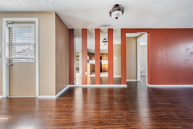 unfurnished room featuring a textured ceiling and dark hardwood / wood-style flooring