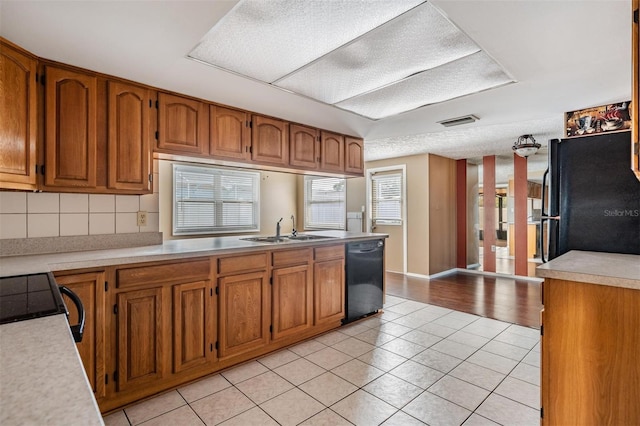 kitchen with tasteful backsplash, light tile patterned flooring, sink, and black appliances