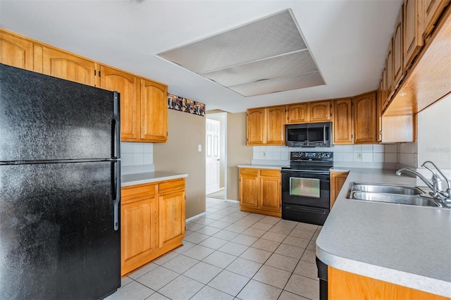 kitchen featuring tasteful backsplash, sink, light tile patterned floors, and black appliances