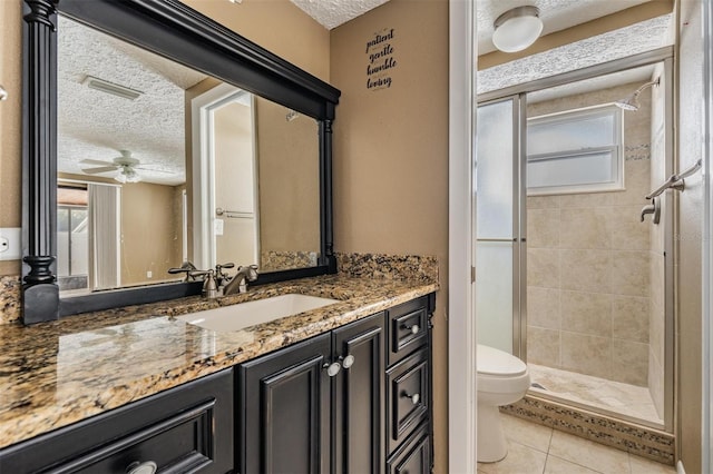 bathroom featuring vanity, toilet, a textured ceiling, and tiled shower