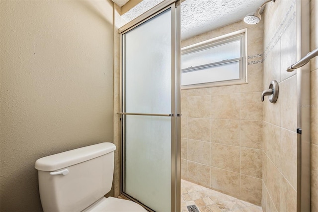 bathroom featuring a shower with door and toilet