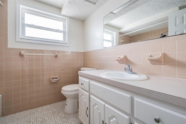 bathroom featuring tile patterned flooring, tile walls, vanity, a textured ceiling, and walk in shower