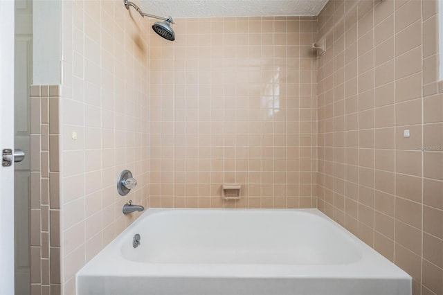 bathroom featuring a textured ceiling and tiled shower / bath