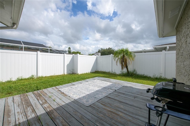 wooden terrace featuring a grill, a lanai, and a yard