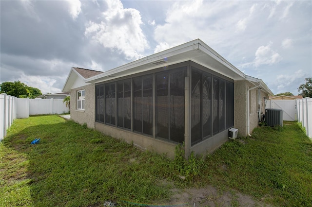 view of side of home featuring a lawn, a sunroom, and central air condition unit