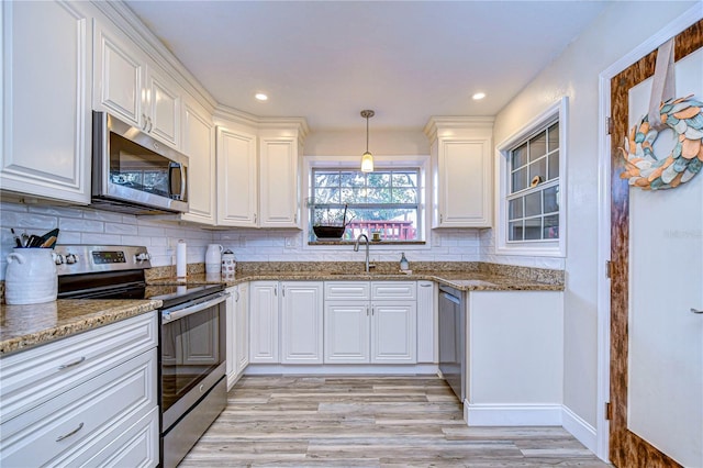 kitchen with pendant lighting, appliances with stainless steel finishes, light stone countertops, and white cabinets