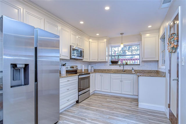 kitchen with sink, decorative light fixtures, appliances with stainless steel finishes, light stone countertops, and white cabinets