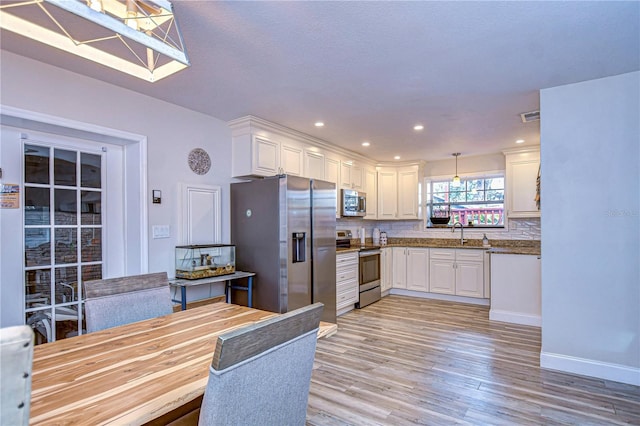 kitchen with white cabinetry, appliances with stainless steel finishes, sink, and pendant lighting