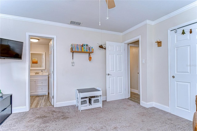 unfurnished bedroom featuring connected bathroom, sink, light colored carpet, ornamental molding, and ceiling fan