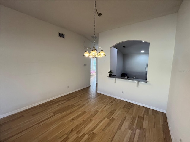 unfurnished dining area with hardwood / wood-style floors and a notable chandelier