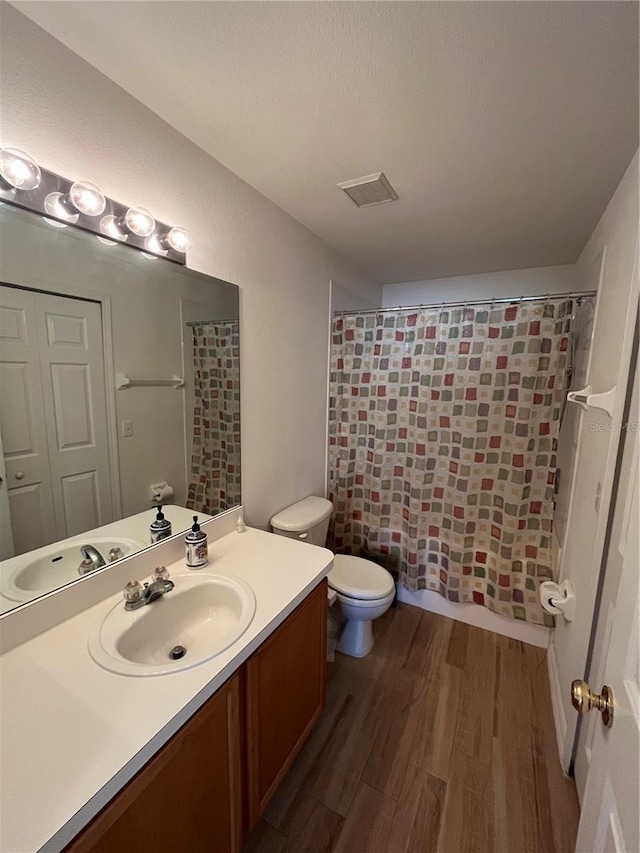 full bathroom featuring toilet, a textured ceiling, vanity, shower / bath combo, and hardwood / wood-style floors