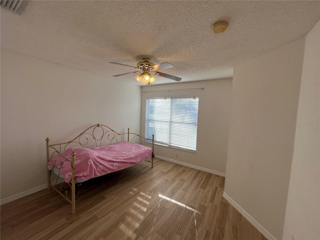 bedroom featuring ceiling fan, a textured ceiling, and light wood-type flooring