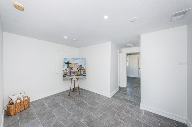 unfurnished room with a textured ceiling, recessed lighting, visible vents, and baseboards