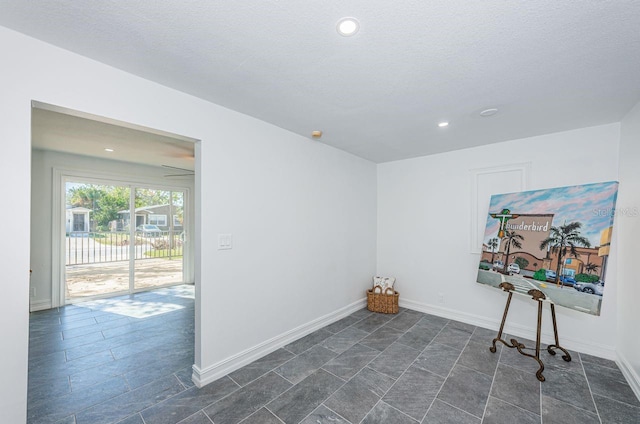 workout area featuring recessed lighting, a textured ceiling, and baseboards