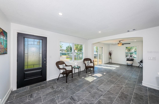 entrance foyer with a healthy amount of sunlight, visible vents, baseboards, and a textured ceiling