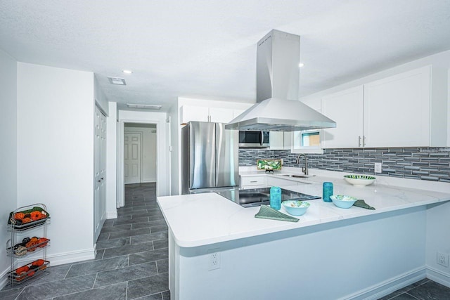 kitchen featuring stainless steel appliances, decorative backsplash, white cabinetry, island range hood, and a peninsula