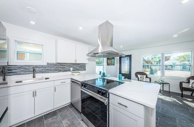 kitchen featuring stainless steel appliances, tasteful backsplash, a sink, island range hood, and a peninsula