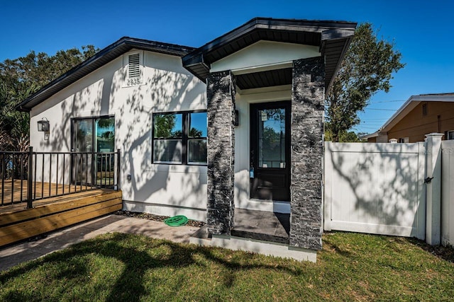 property entrance with fence and a lawn