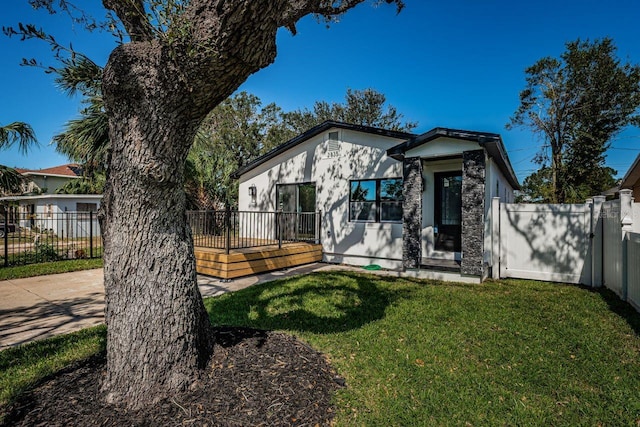 view of front of house featuring a deck, a front yard, fence, and stucco siding