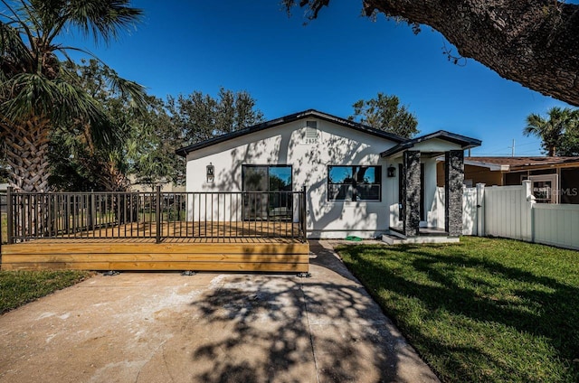 view of front of house with a deck, a front lawn, fence, and stucco siding