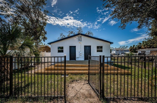 bungalow-style house with a front lawn, fence private yard, a gate, and stucco siding