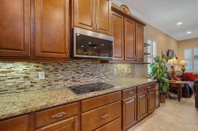 kitchen with decorative backsplash, light tile patterned floors, crown molding, light stone countertops, and black cooktop