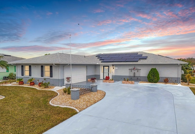 view of front of house featuring a garage, a yard, and solar panels