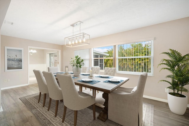 dining area featuring hardwood / wood-style flooring, a chandelier, and a textured ceiling