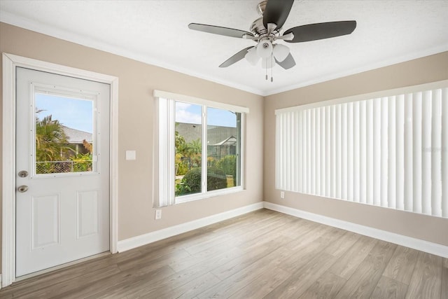 foyer entrance with ceiling fan, ornamental molding, and light hardwood / wood-style flooring