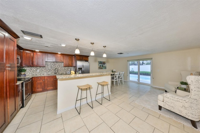 kitchen with a kitchen bar, decorative light fixtures, a center island, stainless steel appliances, and backsplash