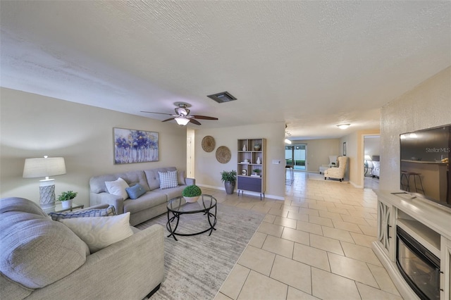 living room with ceiling fan, light tile patterned floors, and a textured ceiling