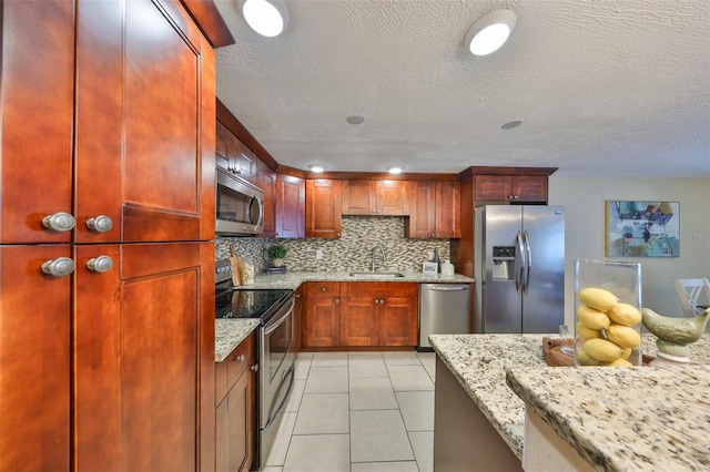 kitchen with light tile patterned flooring, appliances with stainless steel finishes, sink, decorative backsplash, and light stone counters