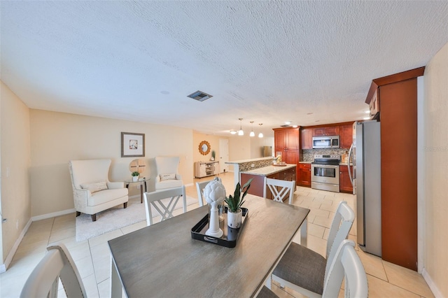 dining space with a textured ceiling and light tile patterned floors