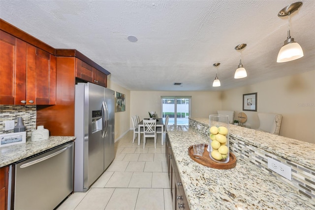 kitchen with stainless steel appliances, decorative light fixtures, light stone countertops, and decorative backsplash