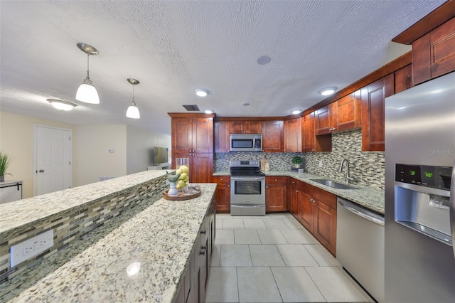 kitchen featuring light stone counters, appliances with stainless steel finishes, decorative light fixtures, and sink