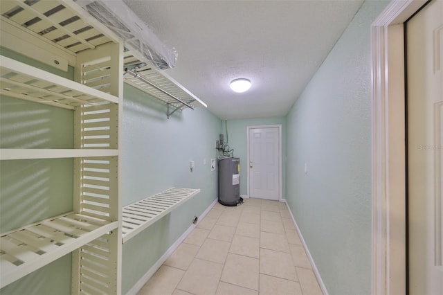 interior space featuring light tile patterned floors, water heater, and a textured ceiling